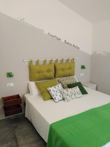 a white bed with green and white pillows on it at Il Ghiro in Levanto