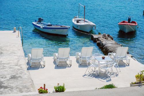 une table, des chaises et des bateaux dans l'eau dans l'établissement Villa Cvita, à Lumbarda