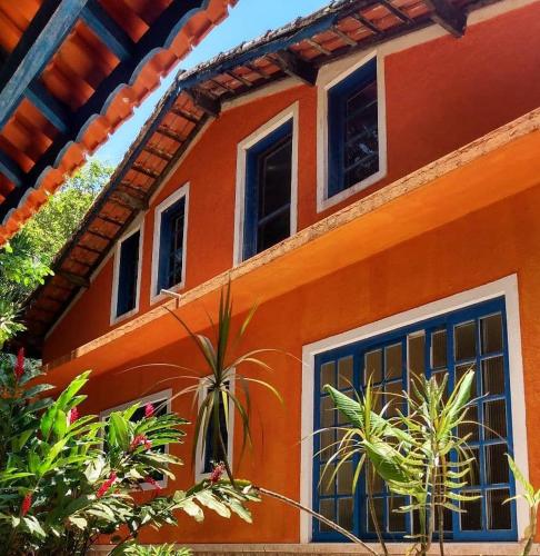 an orange house with plants in front of it at Pousada Sollar Viegas in Peruíbe