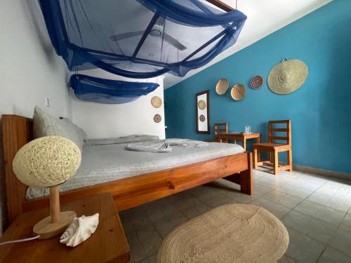 a bedroom with a bed with a blue wall at Highland Bungalows in Nungwi