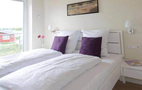 1 Schlafzimmer mit 2 weißen Betten und lila Kissen in der Unterkunft Ferienhaus K�stenweg E in Dagebüll