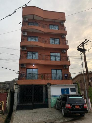 a tall building with a car parked in front of it at Appartement chic et moderne in Douala