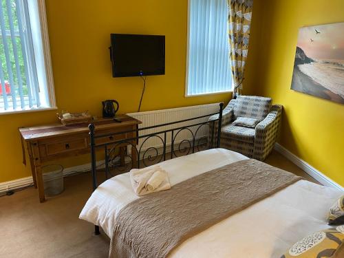 ein Schlafzimmer mit einem Bett, einem Stuhl und einem TV in der Unterkunft The White Horse Inn in Holmfirth