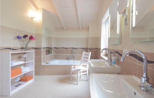 ein Badezimmer mit einer Badewanne, einem Waschbecken und einem Stuhl in der Unterkunft Ferienhaus K�stenweg J in Dagebüll