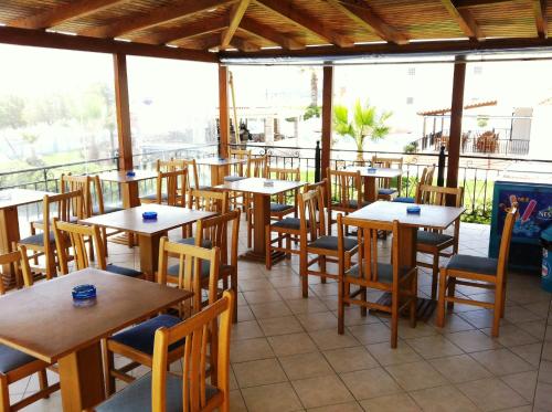 un restaurante vacío con mesas y sillas de madera en Andreolas Beach Hotel, en Laganas
