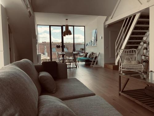 a living room with a couch and a dining room at Lichtrijke loft bij restaurant Den Olifant in Ypres
