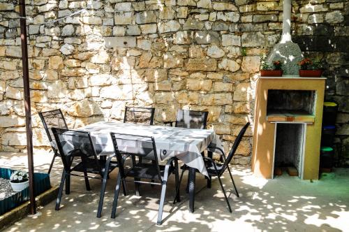 a table and chairs in front of a stone wall at Apartman Gulliver in the center, 10 meters from the sea with private parking in natural shade in Rabac
