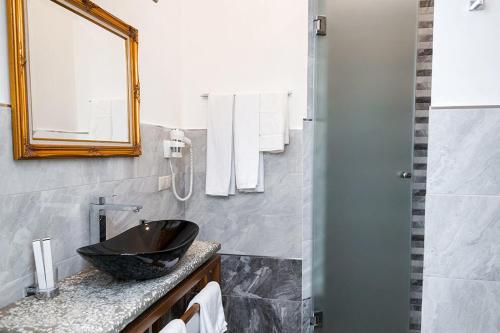 een badkamer met een zwarte wastafel en een spiegel bij Nabat Palace Arbat in Moskou