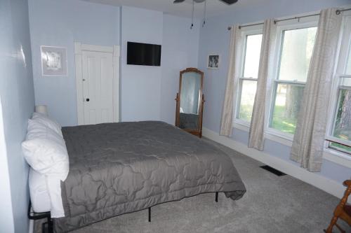 a bedroom with a bed and a mirror and windows at Charlevoix House - The Northside in Charlevoix