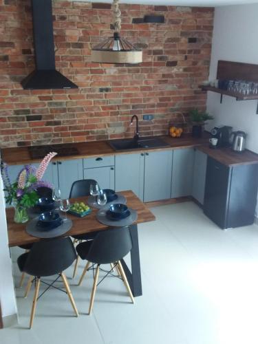 a kitchen with a table and chairs and a brick wall at Dom Gościnny Poza Czasem in Żubracze