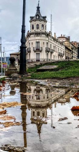 a building with a reflection of a pole in a puddle at MiMA2 JACA in Jaca