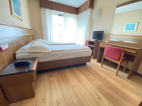a hotel room with a bed and a desk and a television at SunLake Hotel in Riva del Garda