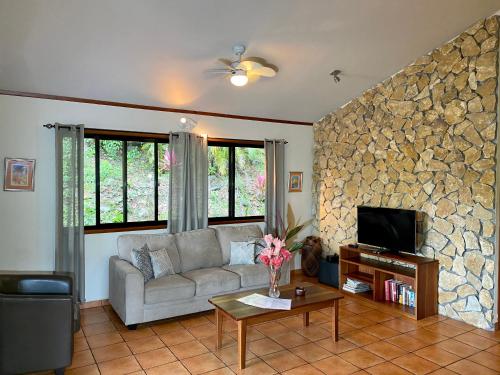 a living room with a couch and a stone wall at Cabanas Rio Encantado in Alto Boquete