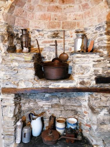a stone fireplace with pots and pans and utensils at La Chouette in Pieve di Teco
