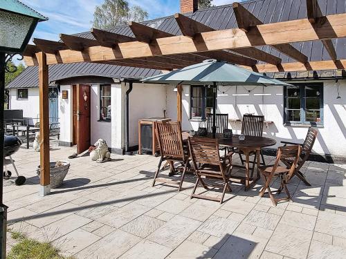 un patio con mesa, sillas y sombrilla en 6 person holiday home in L derup, en Löderup