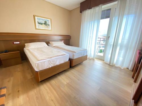 a bedroom with two beds and a large window at SunLake Hotel in Riva del Garda