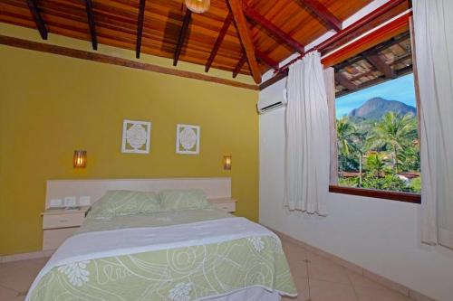 a bedroom with a bed and a large window at VELINN Pousada Villa Caiçara in Ilhabela