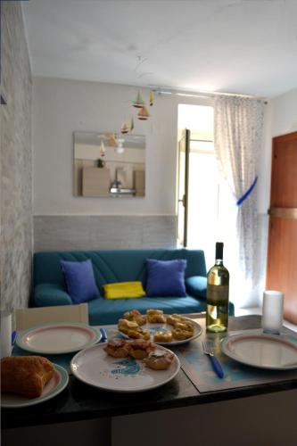 een tafel met borden en een fles wijn bij Via Marina 19 - Casa sul mare. in Buggerru