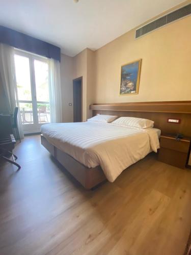 a bedroom with a large bed and a large window at SunLake Hotel in Riva del Garda