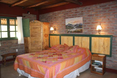 um quarto com uma cama e uma parede de tijolos em El Aleman em Barreal