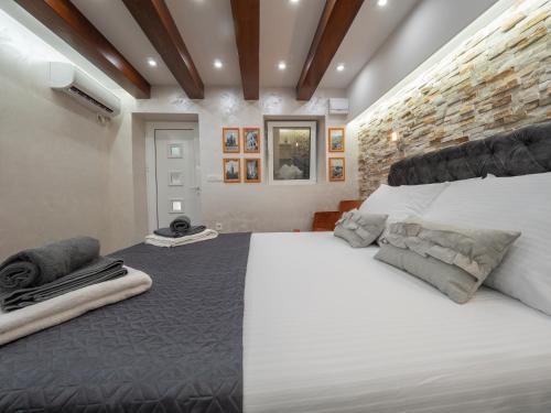 a bedroom with a large white bed and a brick wall at Luxury Boutique Studio in Budva