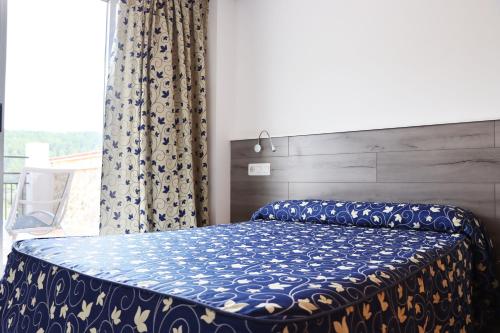 una camera da letto con un letto con un piumone blu e una finestra di Hotel Xauen a Montanejos