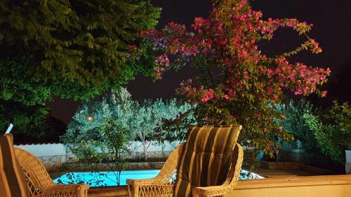 two chairs sitting next to a swimming pool with flowers at Holiday home with pool, Supetar, Island Brac in Supetar