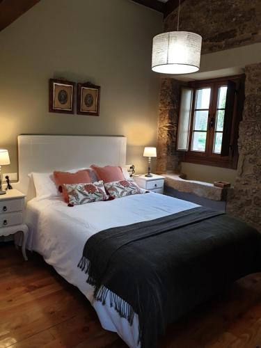a bedroom with a large white bed with pillows at Escola de Bieite in Boimorto