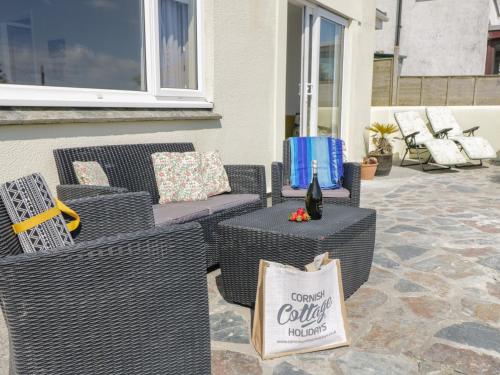 a patio with wicker chairs and a table with a bottle of wine at Wootton Gray in Mousehole