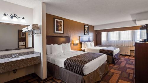 a hotel room with two beds and a sink at Best Western Tower West Lodge in Gillette