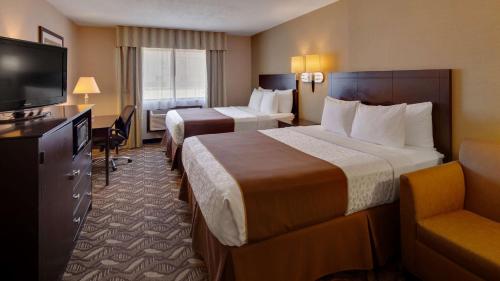 a hotel room with two beds and a flat screen tv at Best Western Pontiac Inn in Pontiac