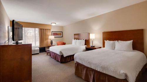 a hotel room with two beds and a flat screen tv at Best Western Cotton Tree Inn in Rawlins