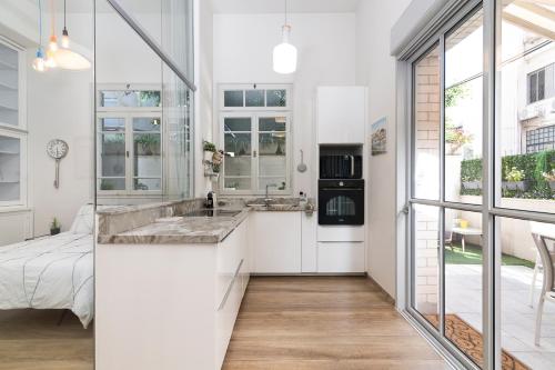 a kitchen with white cabinets and a large window at Allenby 36 Bauhaus Residence 5 Stars in Tel Aviv
