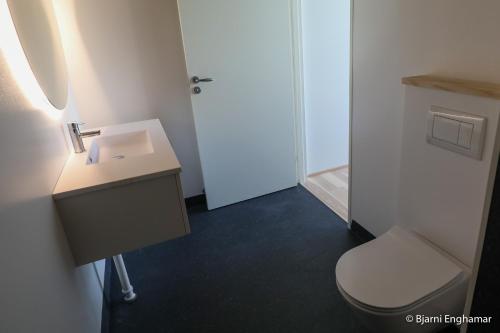 a bathroom with a white sink and a toilet at Mølin Guesthouse in Skálavík