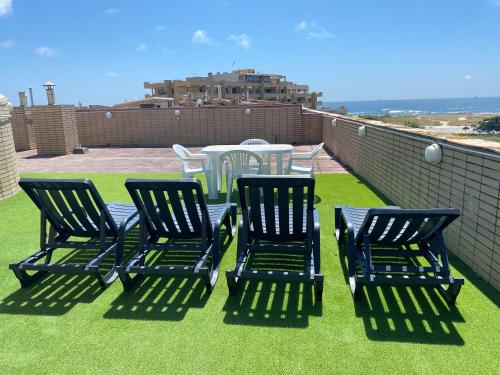 a patio with three chairs and a table on a roof at Beach Front with Rooftop in Vila do Conde
