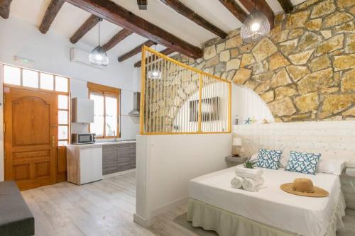 - une chambre avec un lit et un mur en pierre dans l'établissement apartamento loft a 50 metros de la playa y paseo maritimo, à El Campello