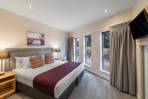 a bedroom with a bed and a tv and windows at Club Wyndham Seven Mile Beach, Trademark Collection by Wyndham in Cambridge