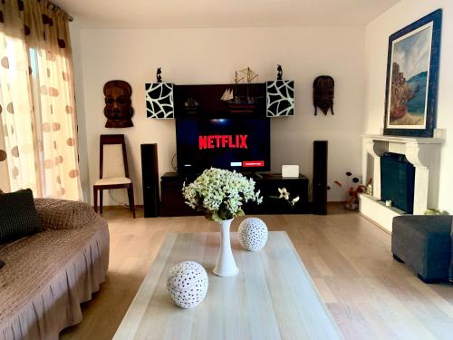 uma sala de estar com televisão e um vaso de flores em Villa Katerina em Stalida
