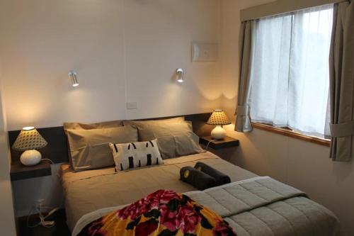a bedroom with a bed with two lamps and a window at OMARU FARM STAY in Ventnor