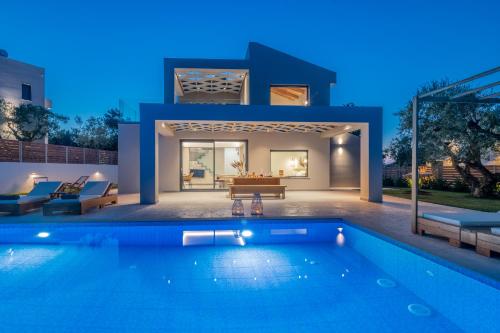 a villa with a swimming pool at night at Villa Plumeria in Tsilivi