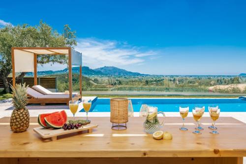 a table with wine glasses and fruit on it next to a pool at Villa Plumeria in Tsilivi