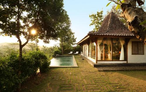 a building with a swimming pool next to a house at Plataran Borobudur in Borobudur