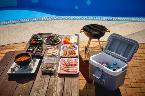 a picnic table with a bunch of food and a grill at Gyeongju Mauna Ocean Resort in Gyeongju