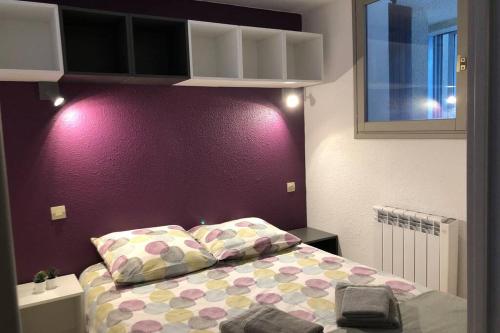 1 cama con 2 almohadas y pared púrpura en Appartement en station de ski en Porté-Puymorens