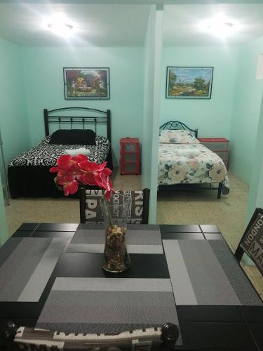 a room with two beds and a table with a vase with flowers at DEPARTAMENTO MUY CERCANO AL AEROPUERTO CD. MEX T2 in Mexico City