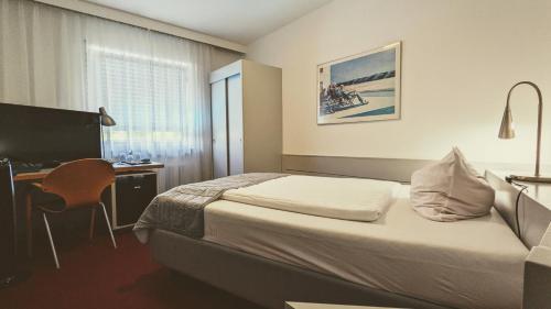 a bedroom with a bed and a desk with a computer at Hotel Rotes Ross in Erlangen