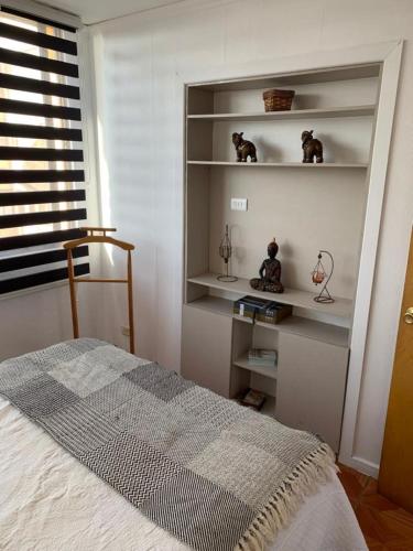 a bedroom with a bed and shelves and a window at Departamento Amoblado Talca in Antofagasta