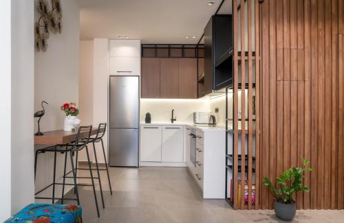 eine Küche mit weißen Schränken und einem Kühlschrank aus Edelstahl in der Unterkunft Glyfada Gallery Apartment in Athen