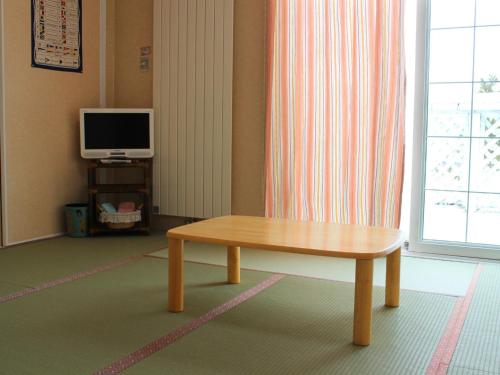 a living room with a wooden table and a television at Furano - Hotel / Vacation STAY 35781 in Furano