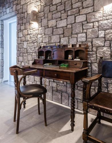a wooden desk with a chair next to a stone wall at Tania Milos in Pollonia